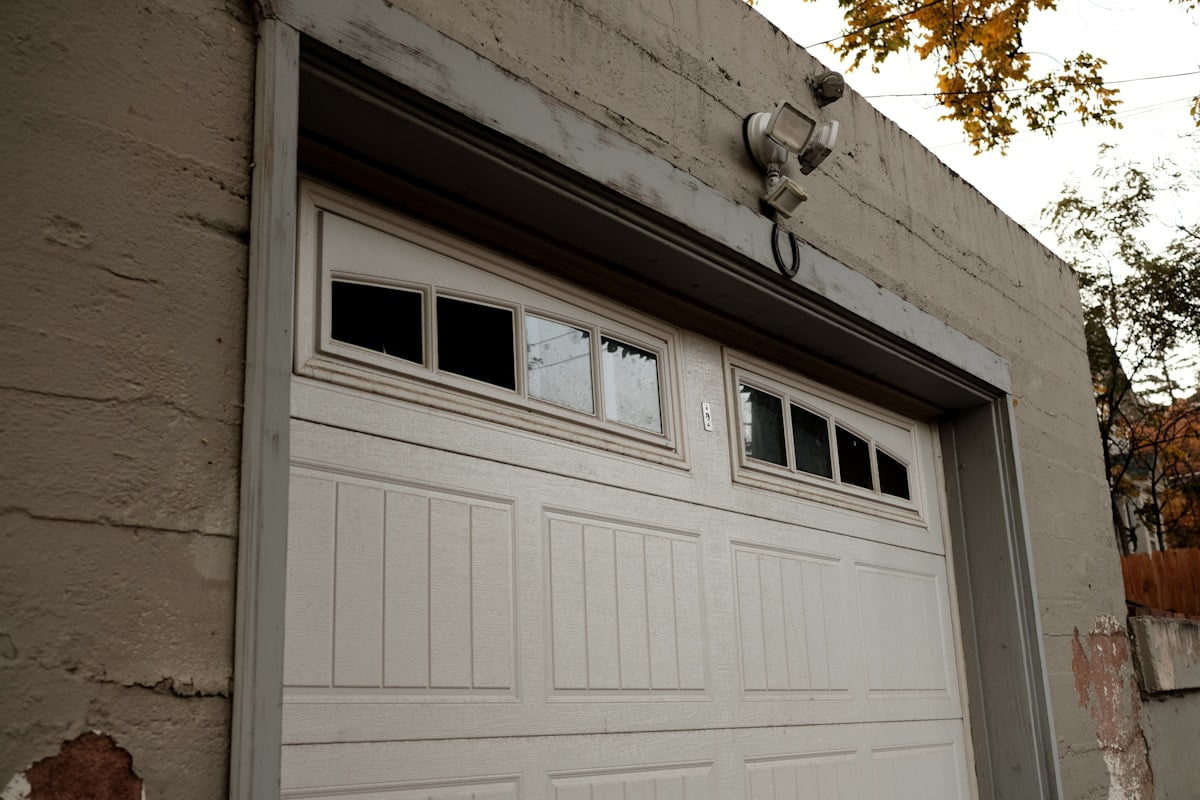 A sectional garage door with a row of glazed panels, on a weathered plastered building.