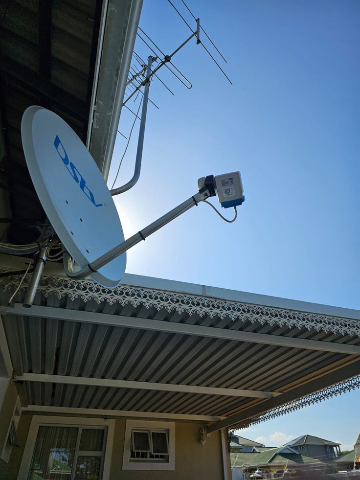 A satellite dish we installed on a corrugated roof, aligned against a clear Cape Town sky.