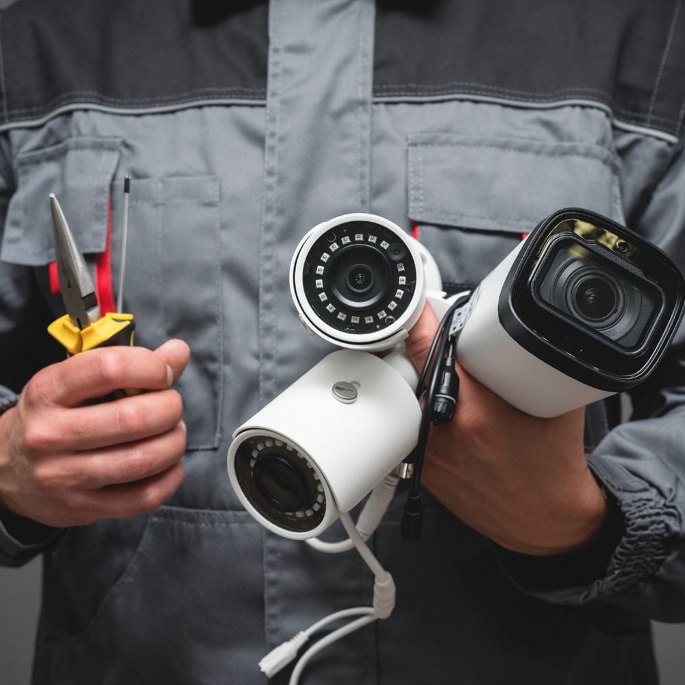 One of our technicians holding the bullet and dome cameras used on a typical installation.