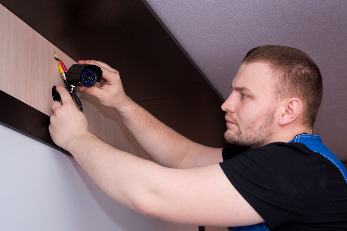An installer wiring a wall unit, screwdriver in hand and the faceplate off.