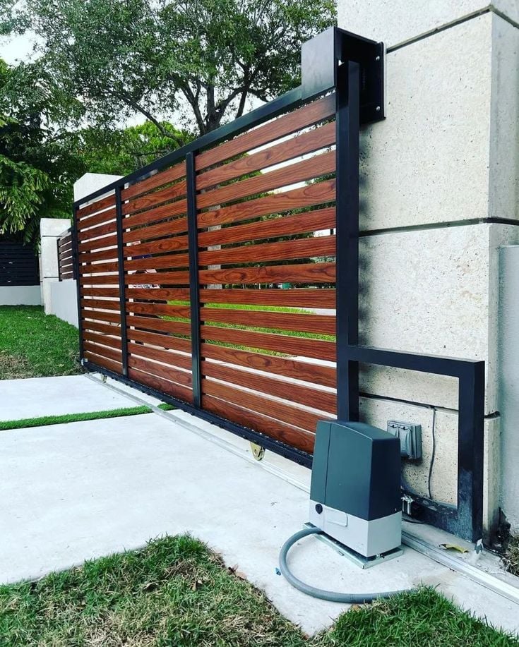 A sliding gate motor installed at a driveway entrance, bolted down and set up.